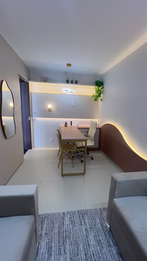 Vista da entrada da sala, com mesa ao fundo e painel iluminado